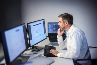 Denkströme IT-Spezialist arbeitet konzentriert an mehreren Monitoren – Softwareentwicklung und Programmierung im modernen Büro