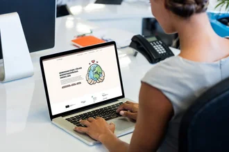 Frau am Schreibtisch betrachtet die Website des Landratsamts Oberallgäu auf dem Laptop – modernes responsives Webdesign mit Fokus auf Klimawandelanpassung und regionale Resilienz